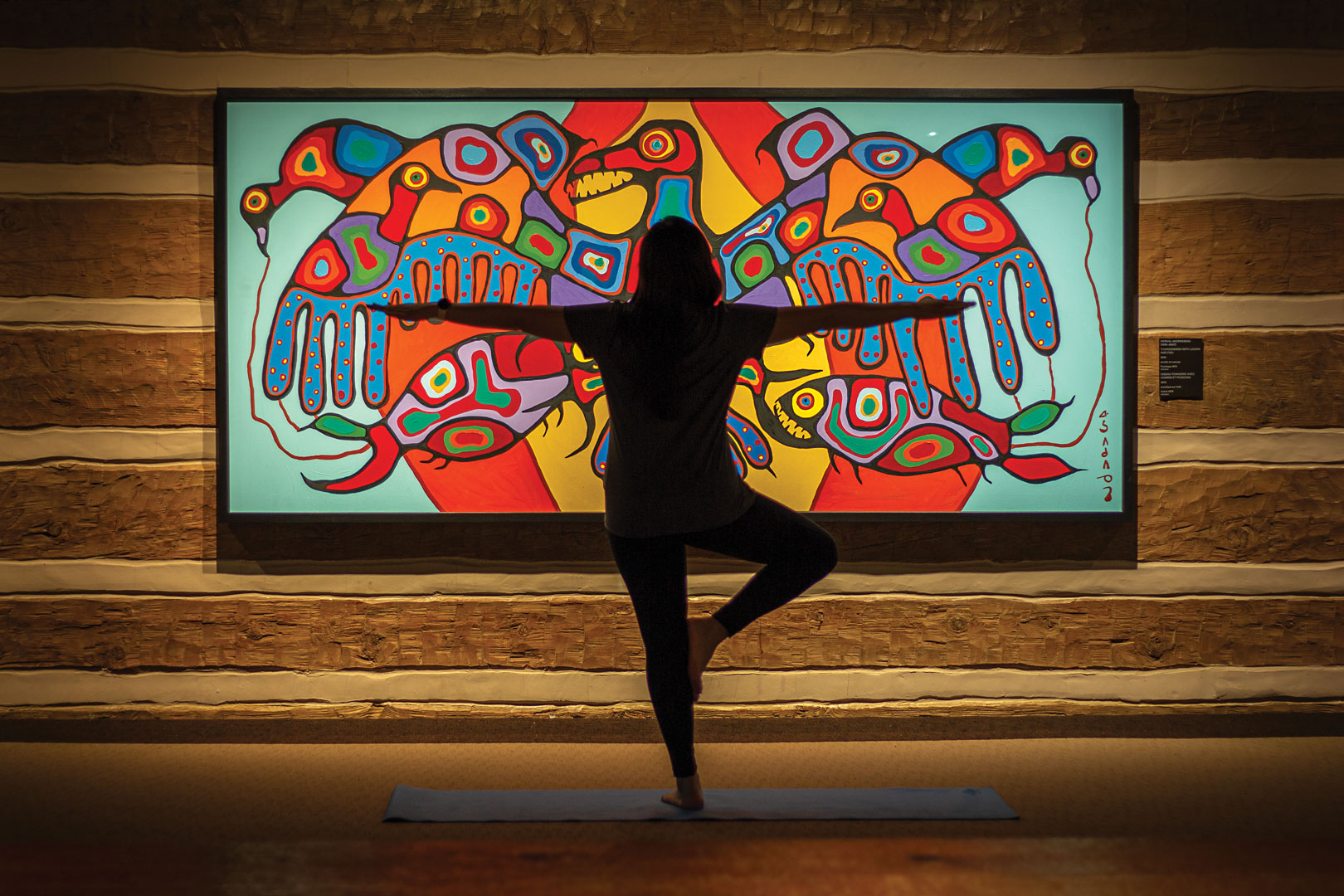 Person in yoga pose in front of colour West Coast artwork in a gallery
